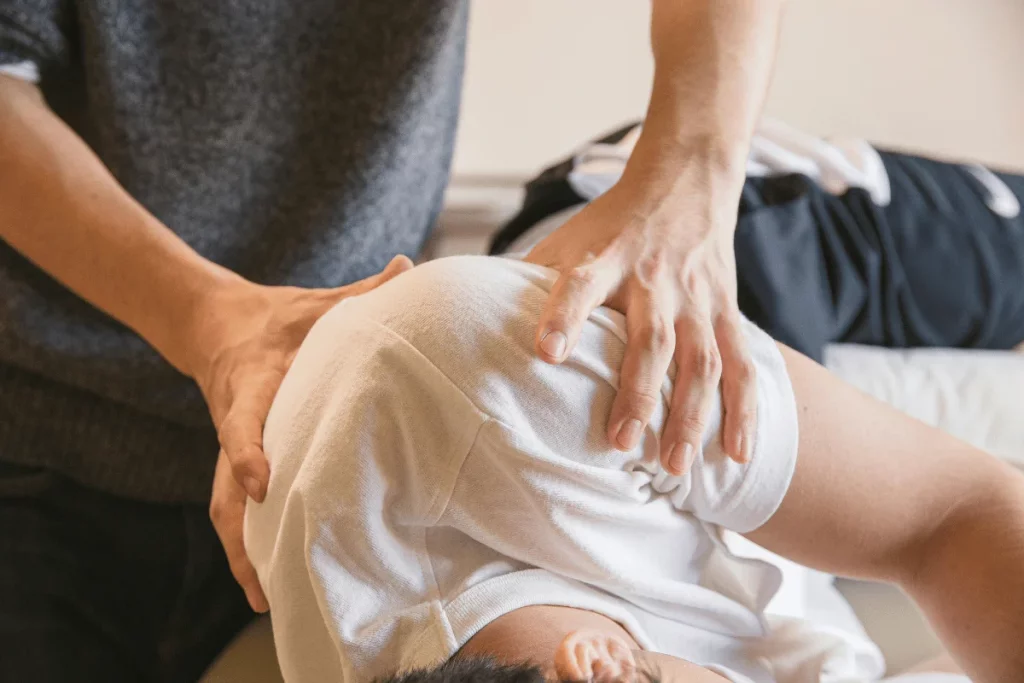 Chiropractor adjusting a patient’s back during a therapy session.