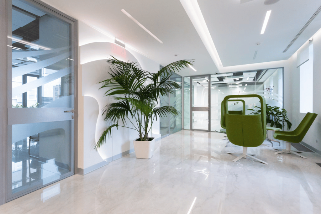 A modern office with white walls and green chairs.