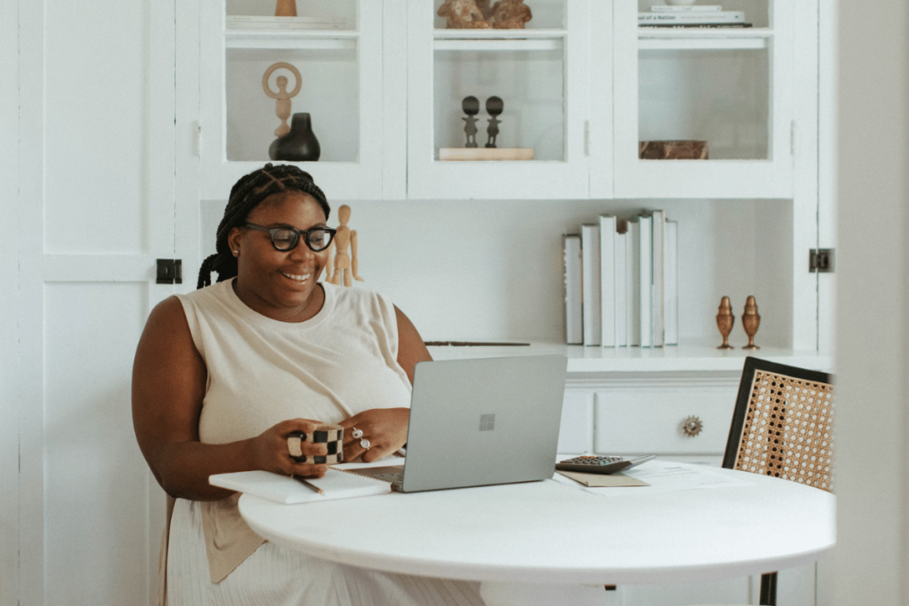 A person sitting at a white table with a laptop.