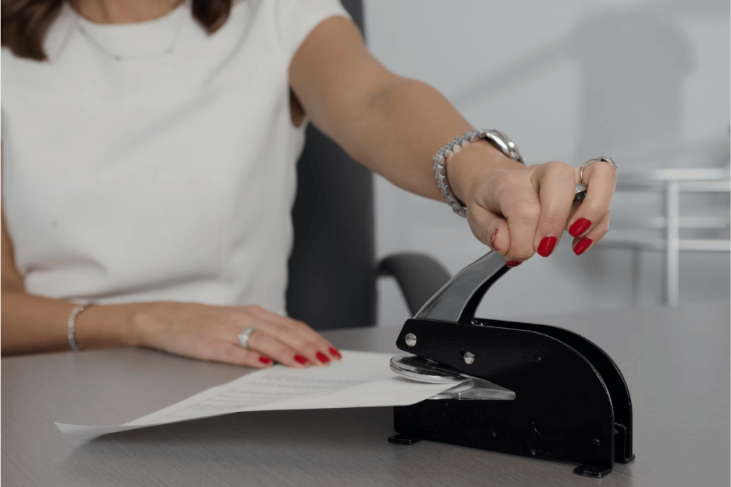 A person using a stapler to open a piece of paper.