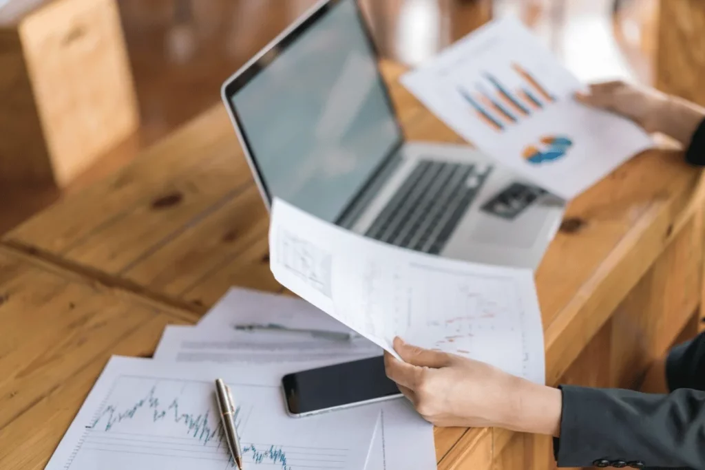 Businessperson analyzing charts and graphs at a wooden desk.