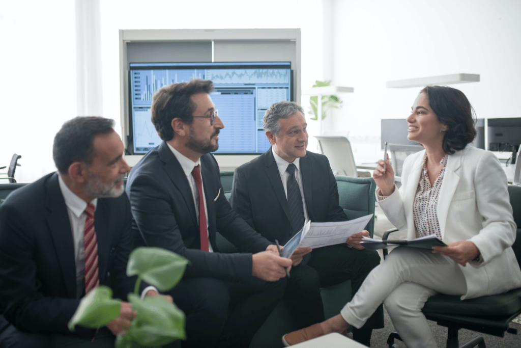Business executives in discussion with documents in a bright office.