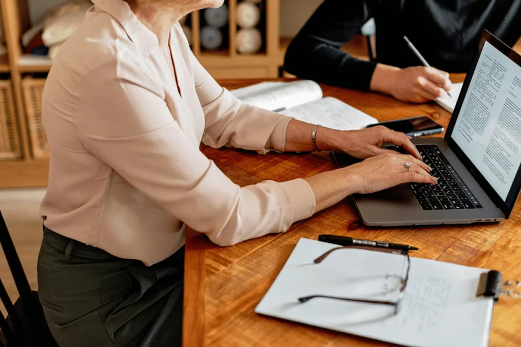 Businesswoman typing on a laptop during a meeting.