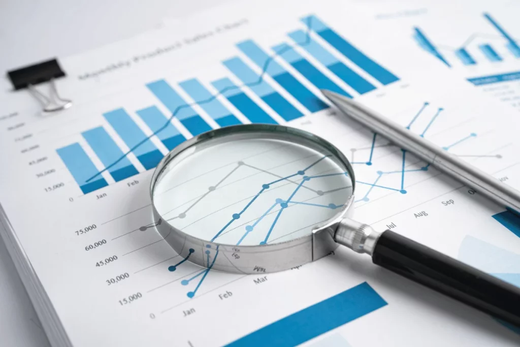 Close-up of a magnifying glass over financial charts and graphs.
