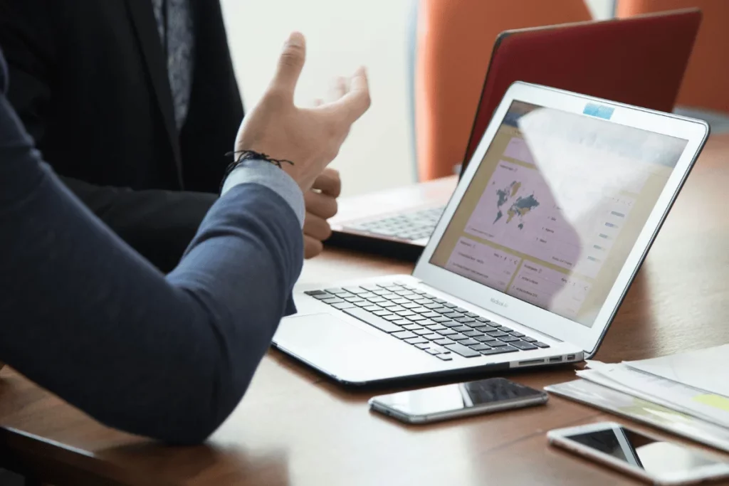 Business professionals discussing data displayed on a laptop screen.
