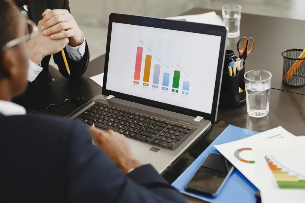 Executives discussing a bar chart on a laptop during a meeting.