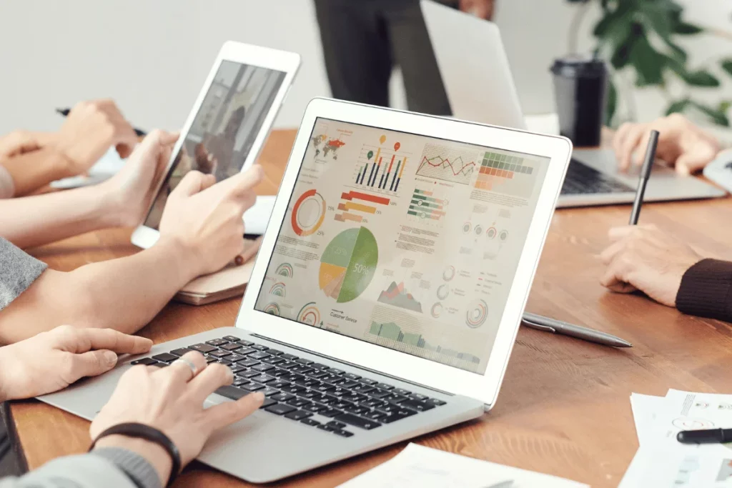 Team reviewing business analytics and charts on a laptop screen.