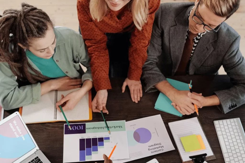 Overhead view of a collaborative team analyzing marketing charts on a desk.