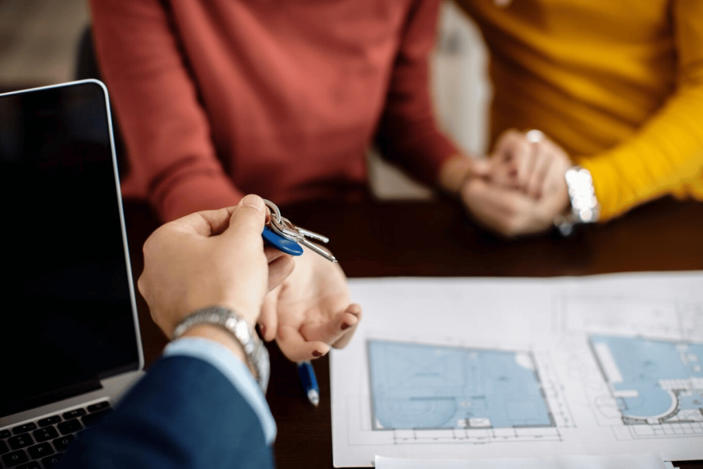 Two people sitting at a table with a laptop and keys.