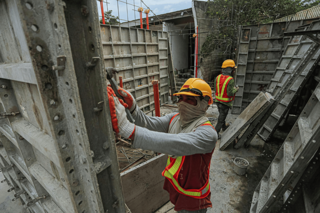Construction workers in safety gear assembling concrete formwork.