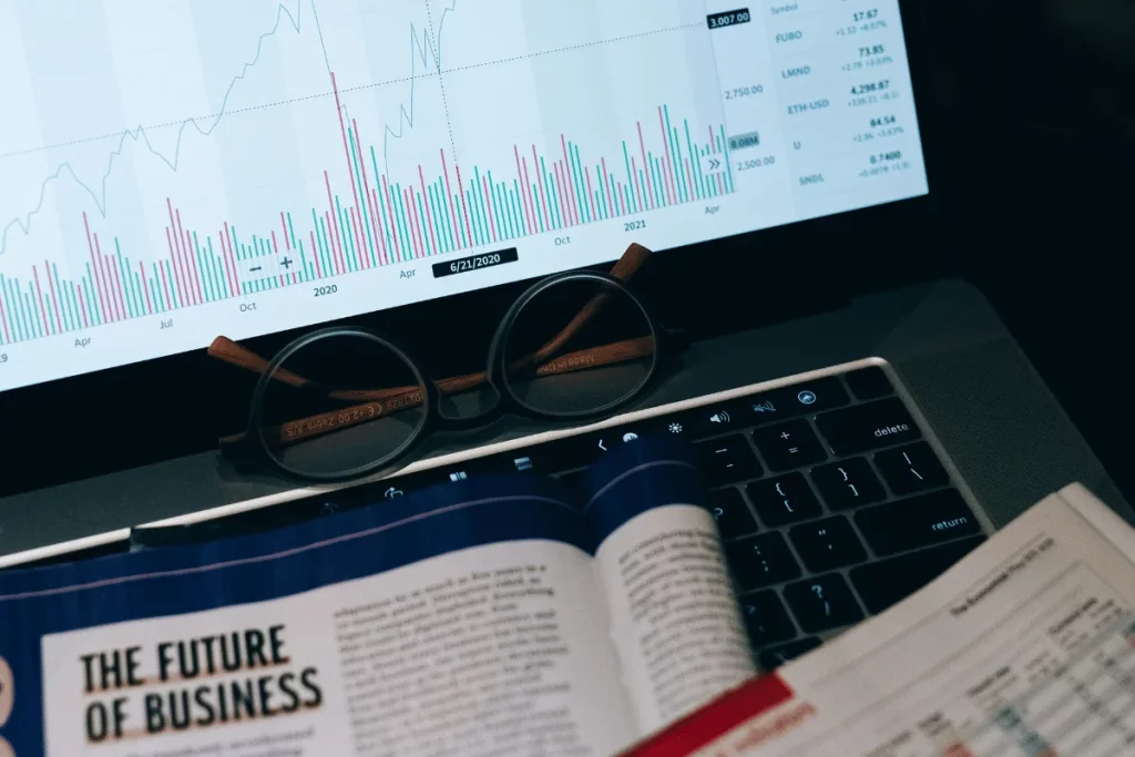 Financial analysis on a laptop with a business magazine and eyeglasses in the foreground.