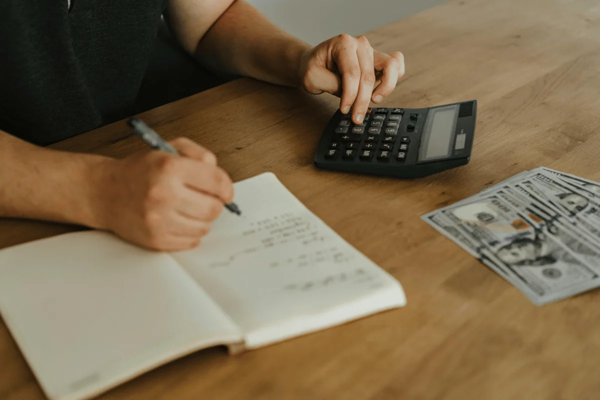 Person calculating finances with notebook and cash.