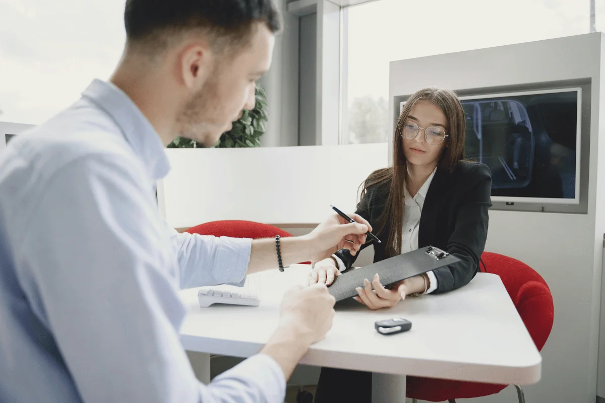 Businesswoman holding a clipboard while discussing documents with a colleague.