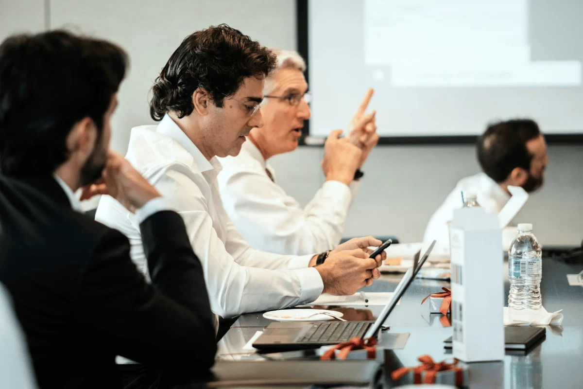 Team of executives in formal attire discussing during a boardroom meeting.