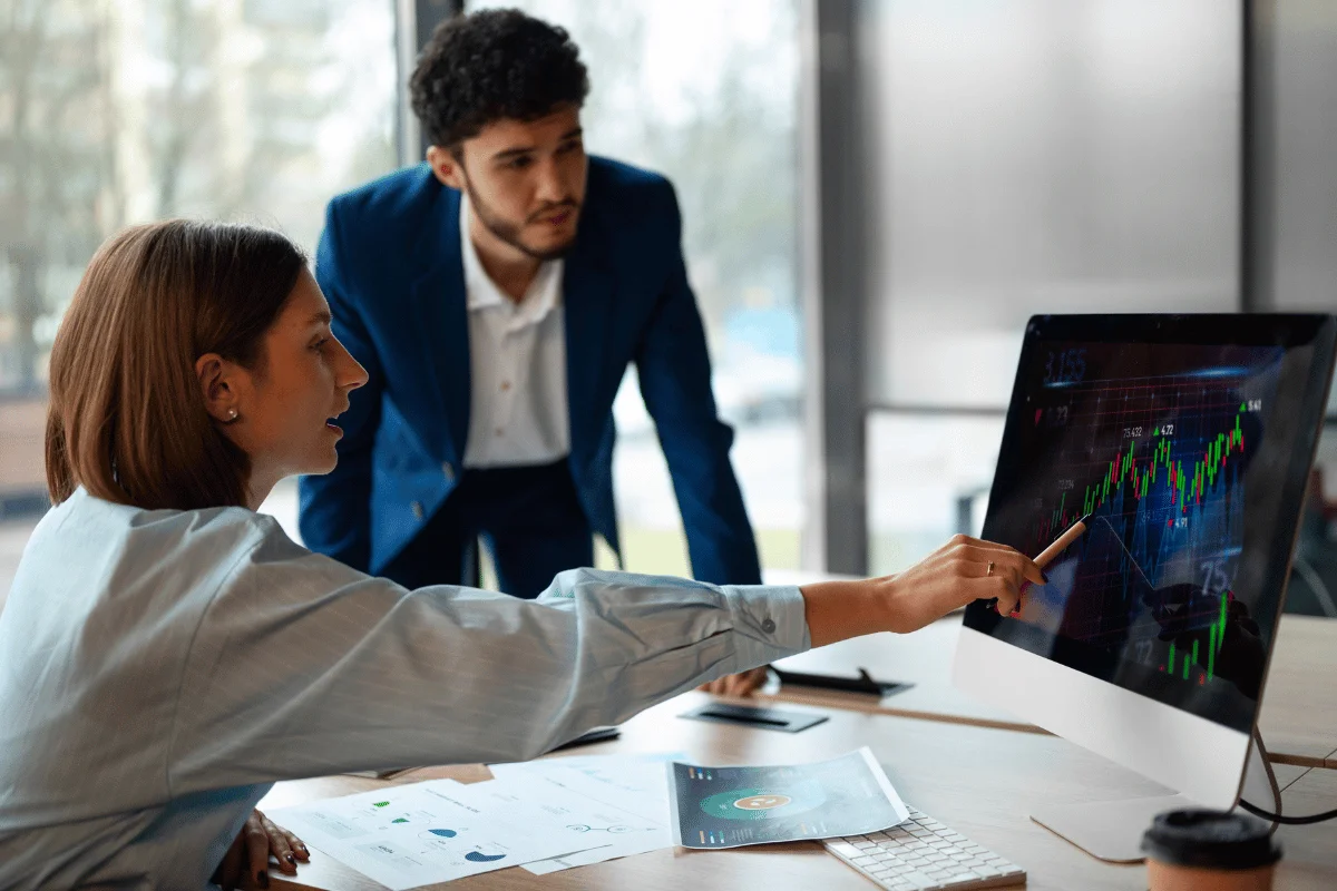 Woman pointing at digital graph during financial meeting with colleague.