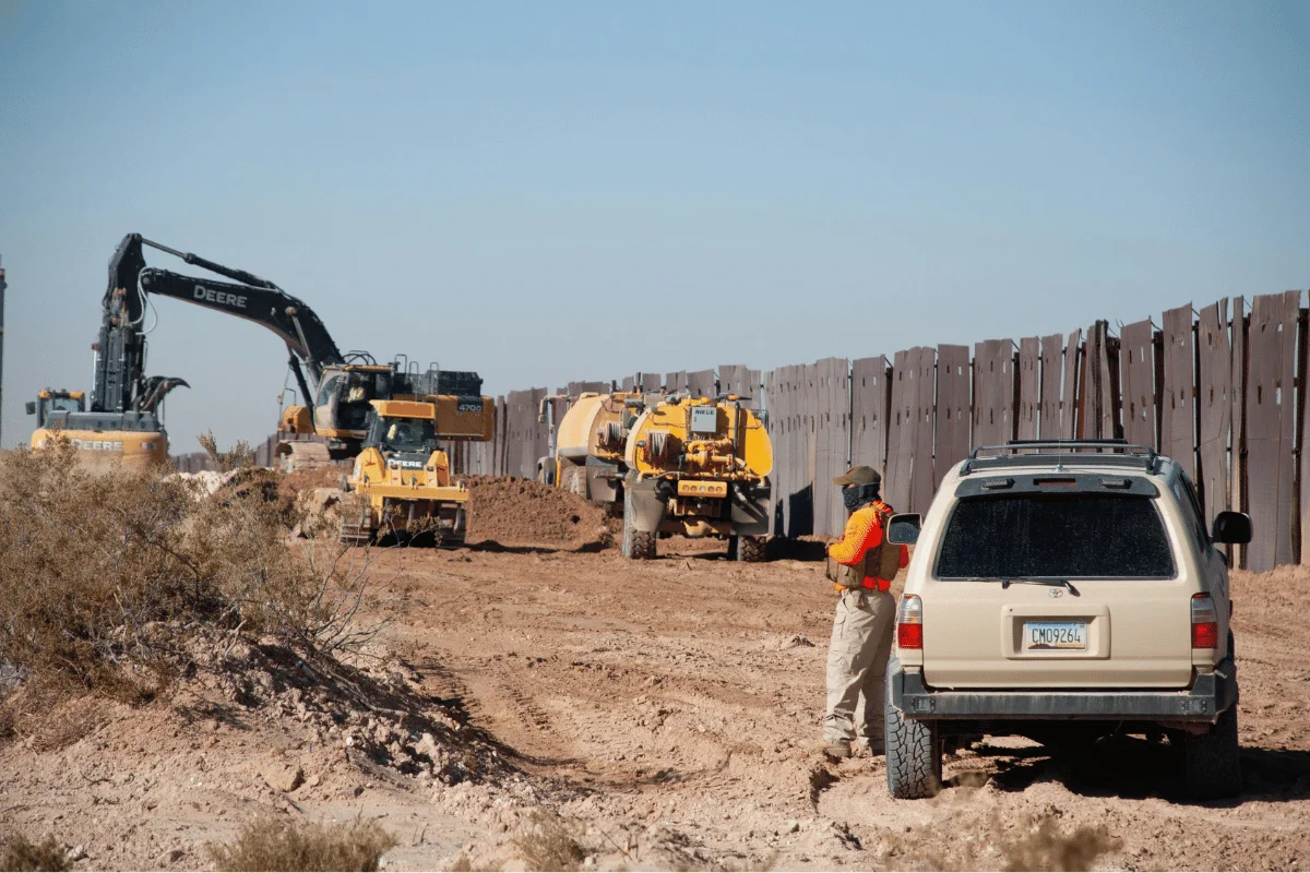 Construction site with heavy machinery and a worker supervising.
