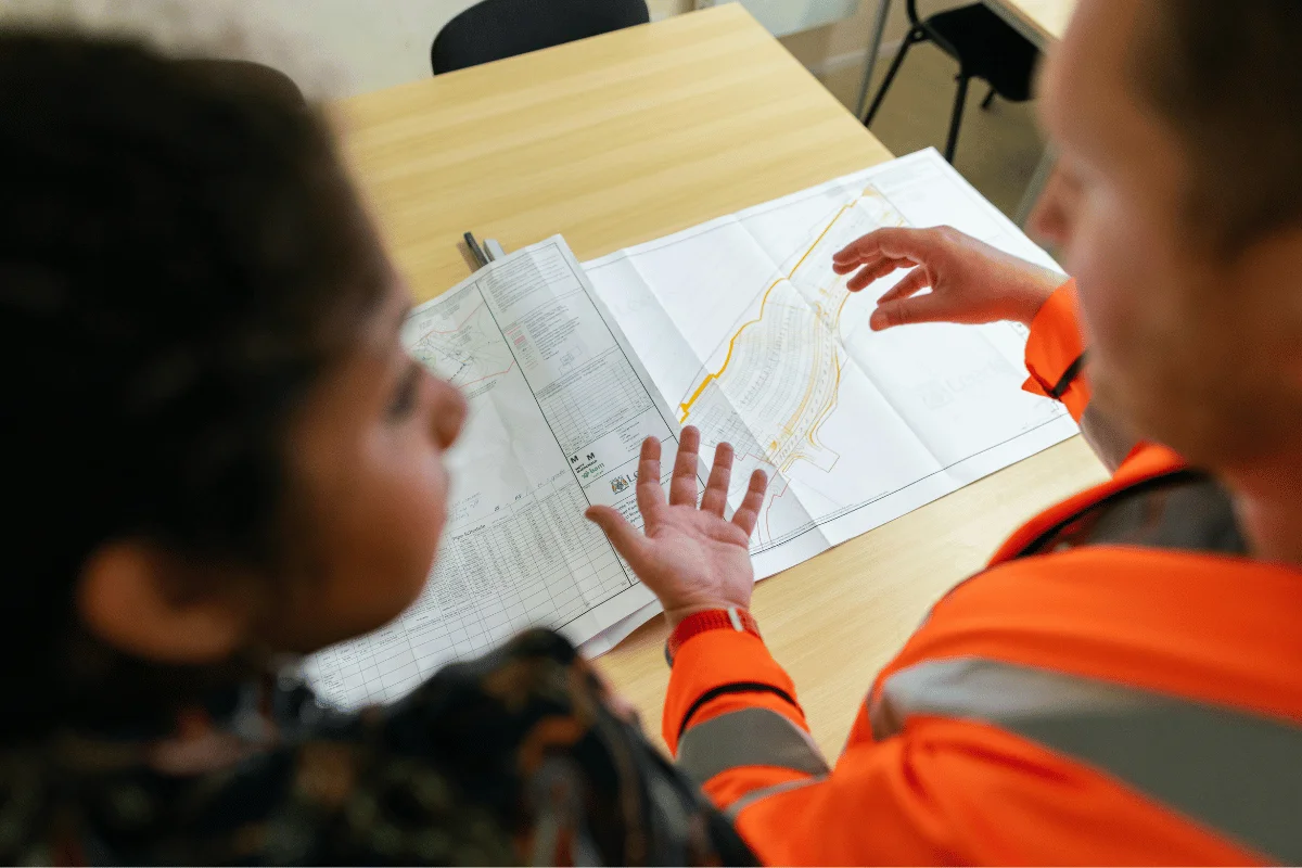 Construction workers in high-visibility vests reviewing architectural blueprints.