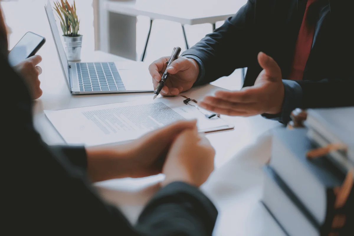 Two professionals reviewing legal documents and taking notes during a meeting.