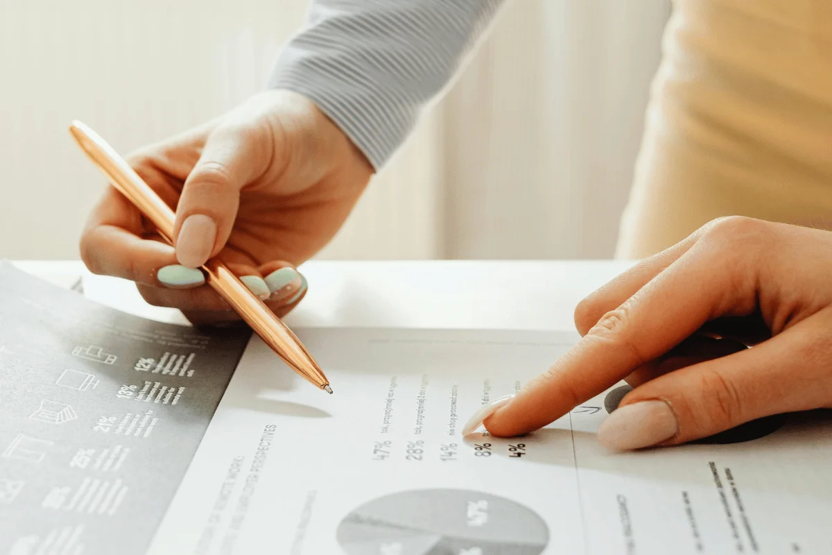 The second hand, with manicured nails, emphasizes a specific section of the chart on the page.