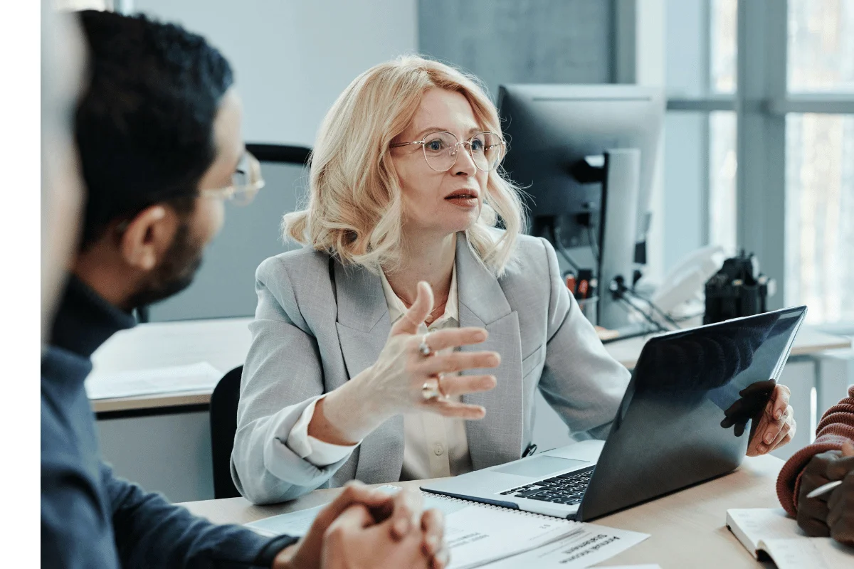 Female executive explaining strategy with laptop and documents.