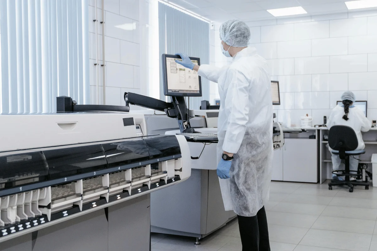 Scientist in lab coat using touchscreen panel for medical testing.