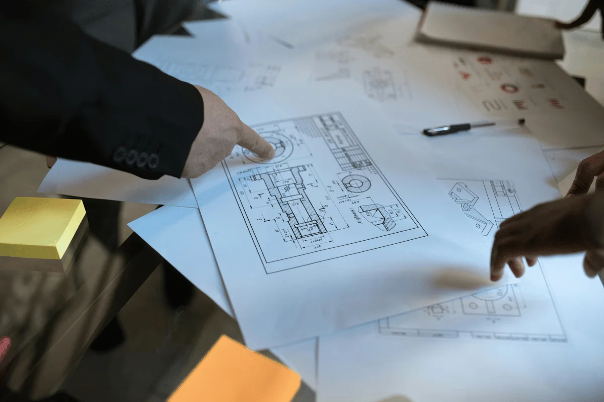 Architects reviewing detailed engineering drawings on a well-lit drafting table.