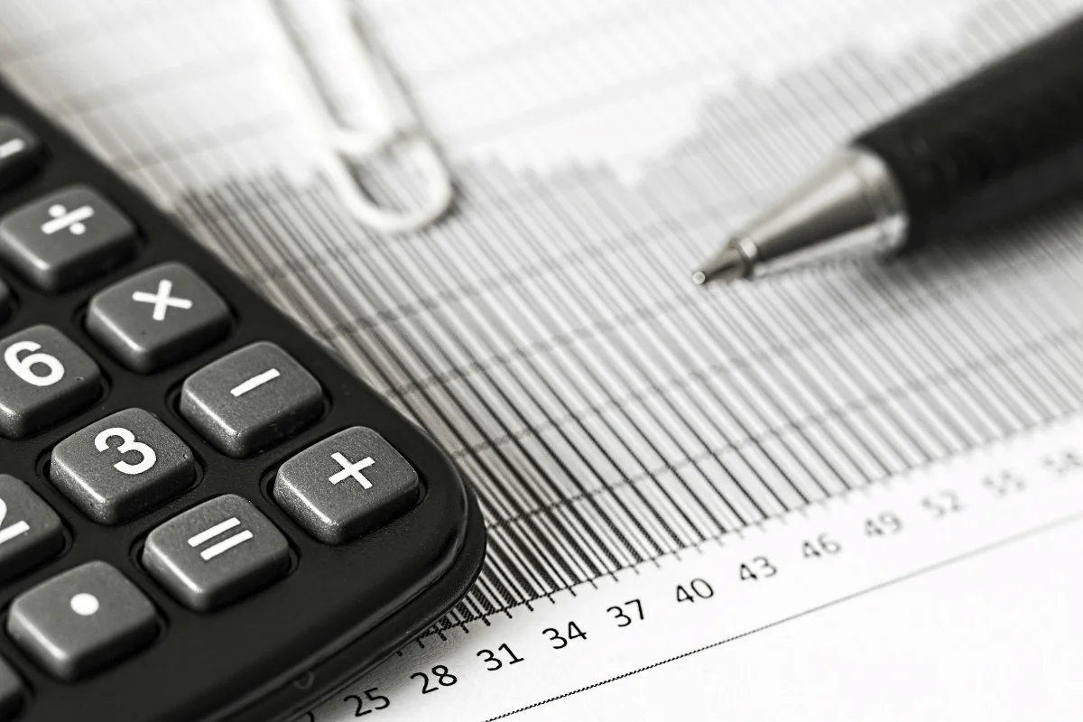Close-up of a calculator and pen placed on financial charts, representing calculations and data analysis.