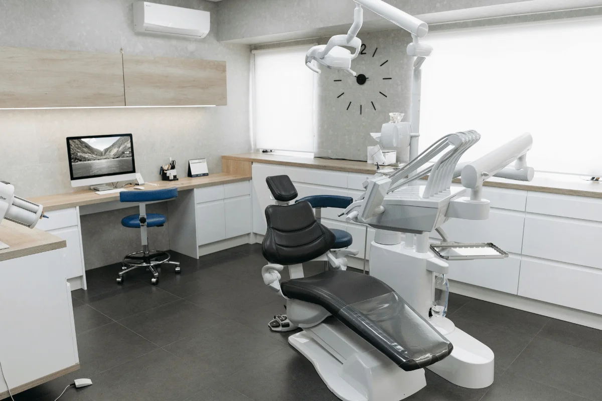 Modern dental clinic interior featuring a dental chair, workstation with a computer, and minimalist decor. Bright and inviting atmosphere.