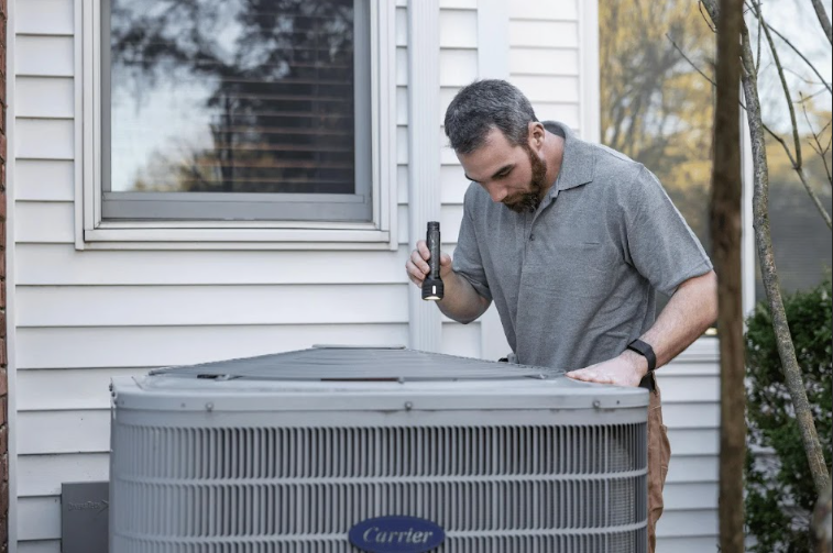 HVAC technician inspecting residential outdoor air conditioning unit during service visit.
