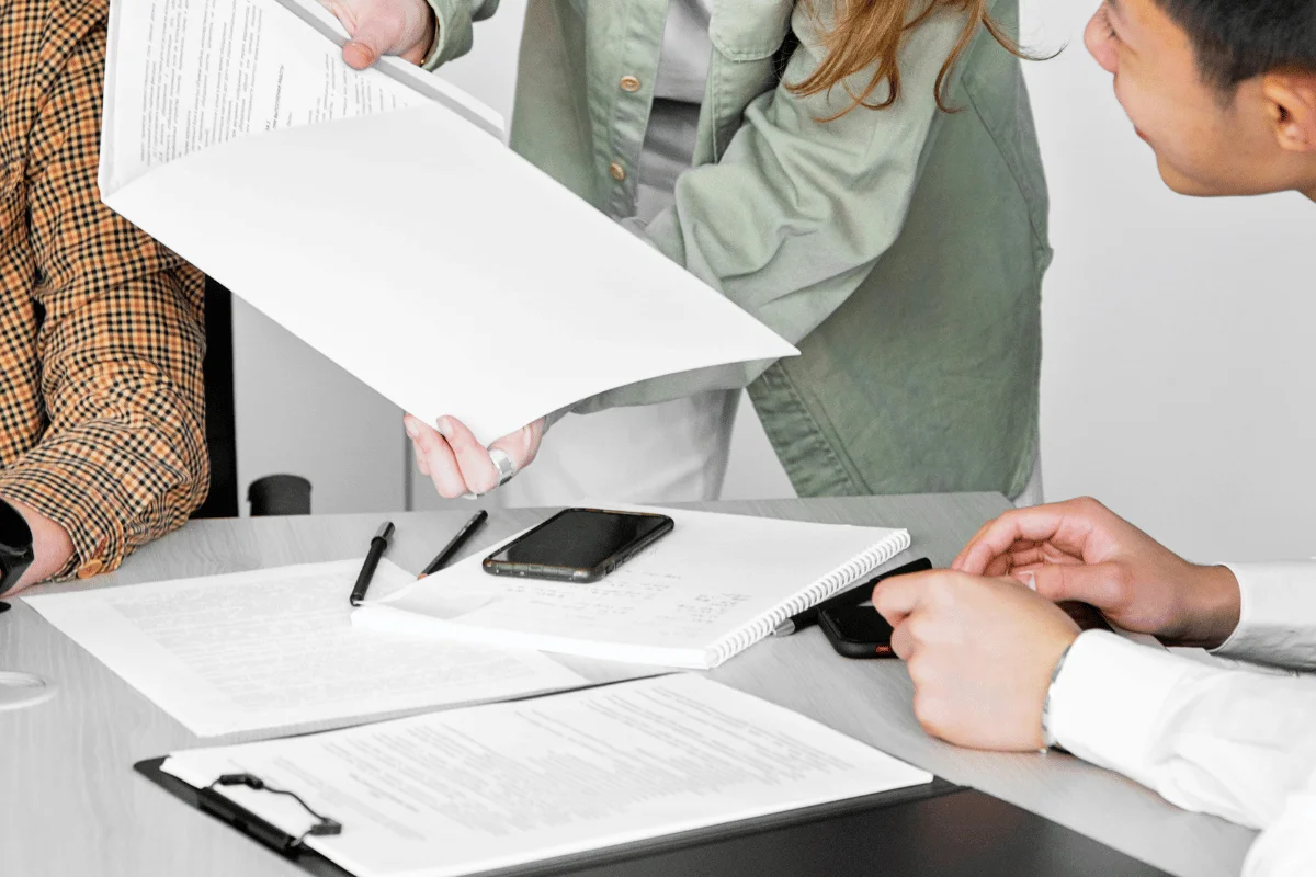 A group of professionals discussing documents and working on paperwork at a meeting table.