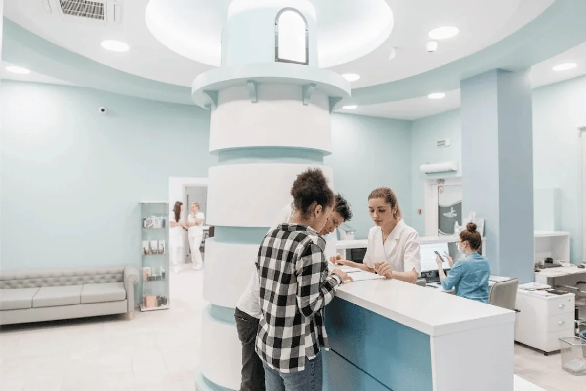 People standing at the reception counter of a medical clinic.
