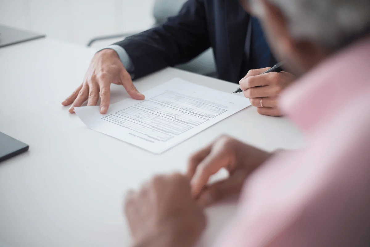 Two business professionals discussing a document during a meeting, with one person signing the paper.