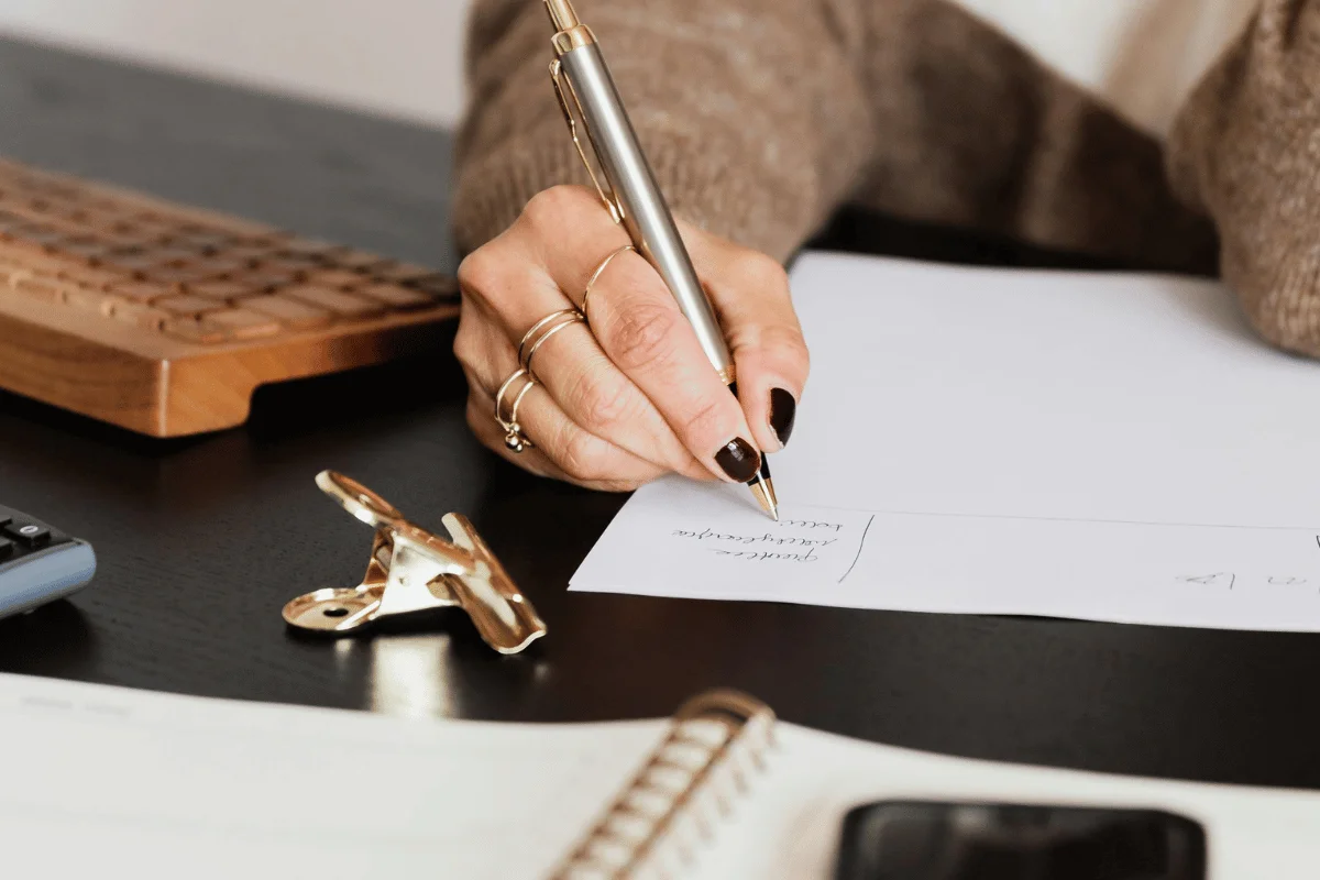 Woman with black nail polish writing notes.