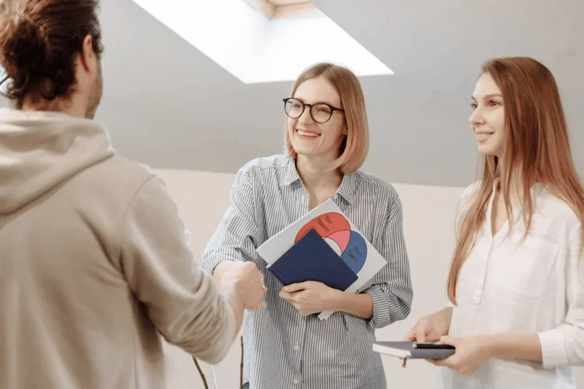 Two HVAC professionals shaking hands with homeowner while discussing how to value a heating and air condition system.