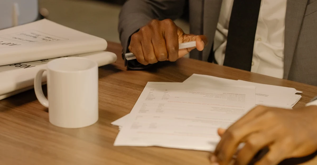 A professional reviewing documents at wooden desk with coffee mug before market preparation to sell SaaS company.