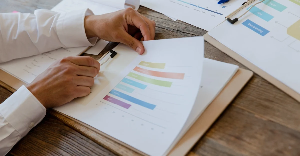 Person analyzing colorful timeline chart showing SaaS exit strategy planning options on wooden desk.