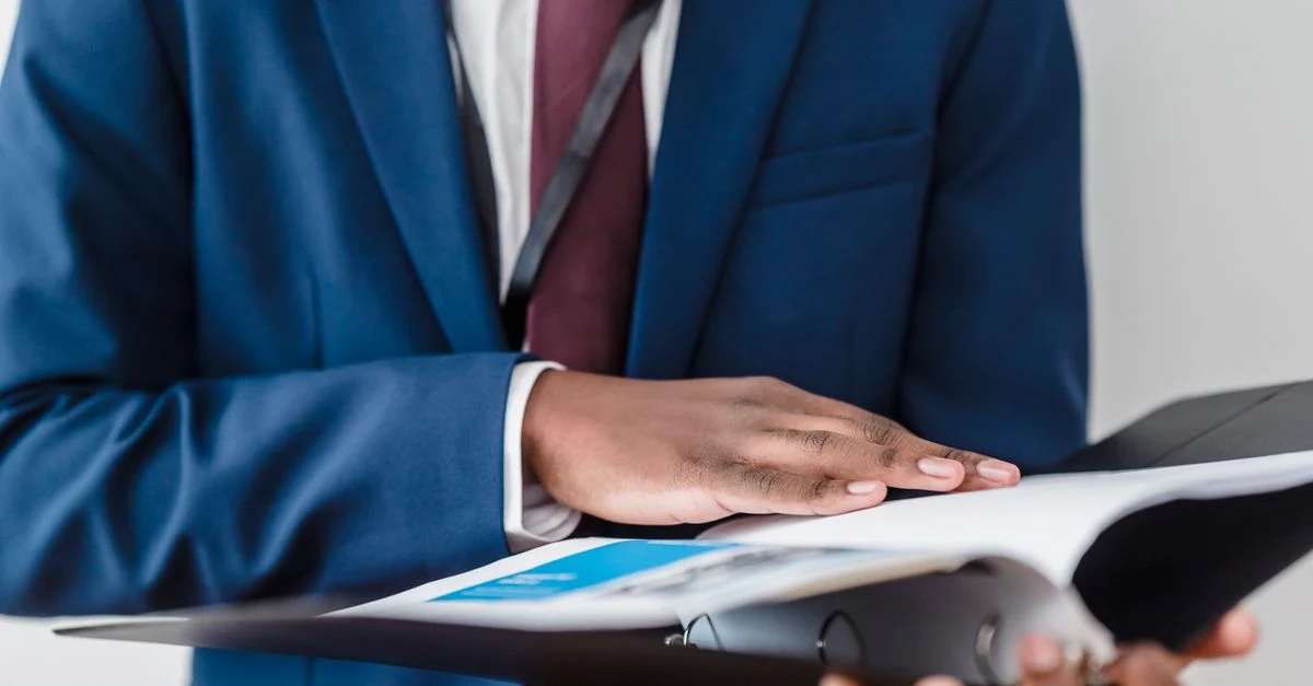 Businessman in blue suit reviewing financial documents during SaaS M&A due diligence process.