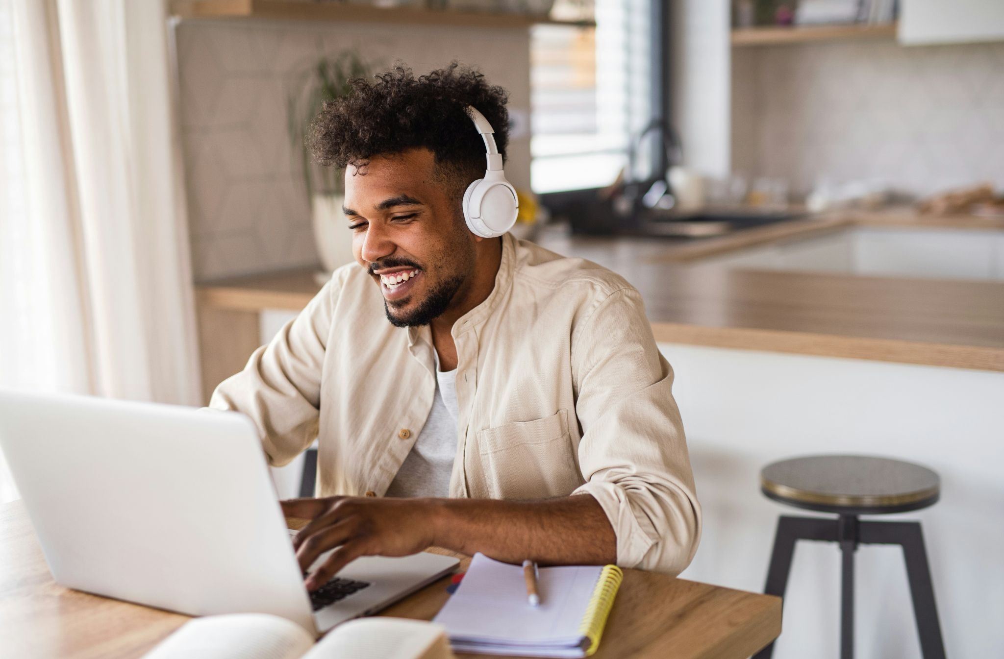 Teacher wearing headphones while using virtual classroom software to deliver an online lesson from a computer.