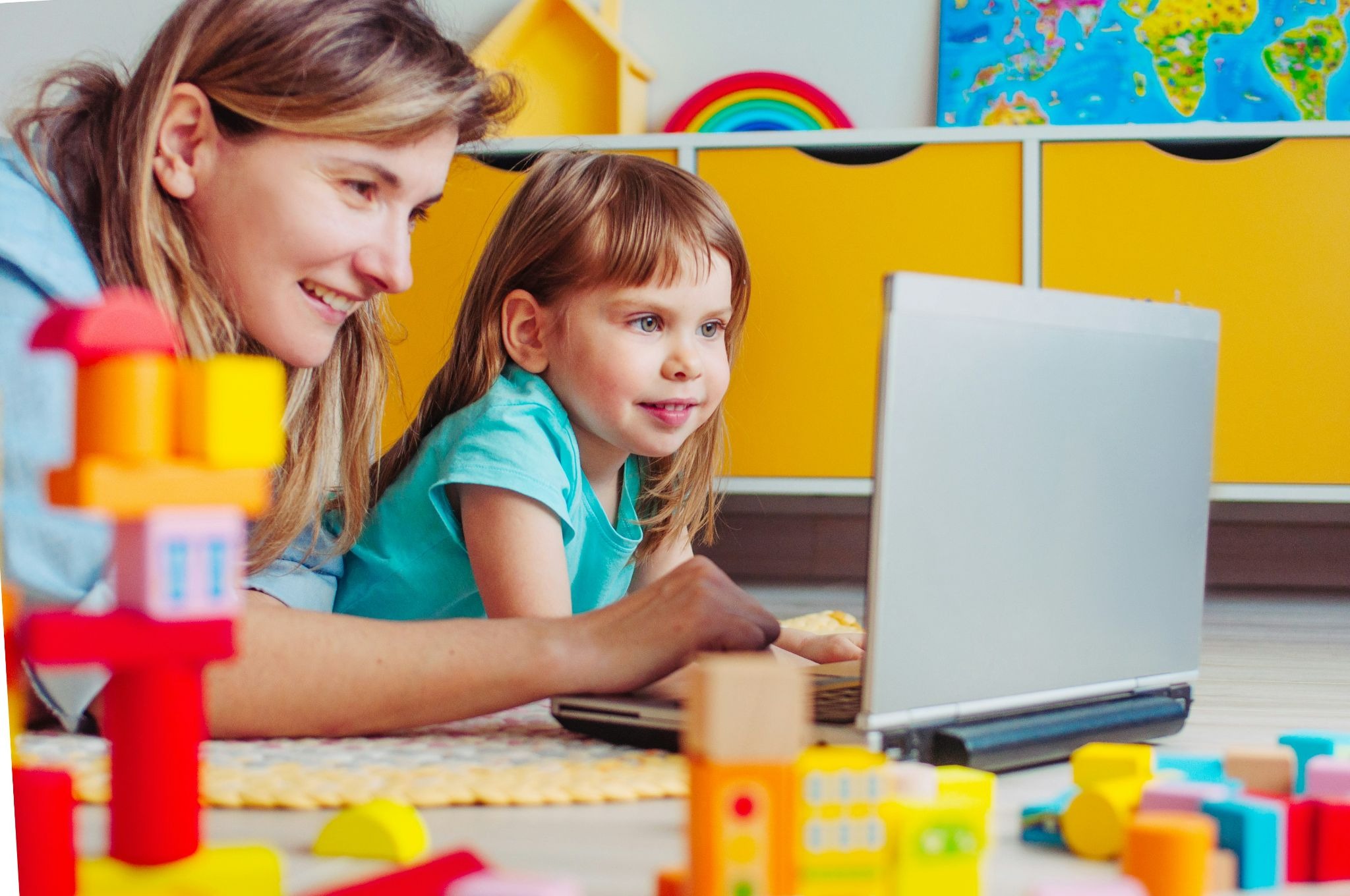Mother supervising her daughter during an online reading tutoring session in a virtual classroom, with the student participating in a live literacy lesson on a laptop.
