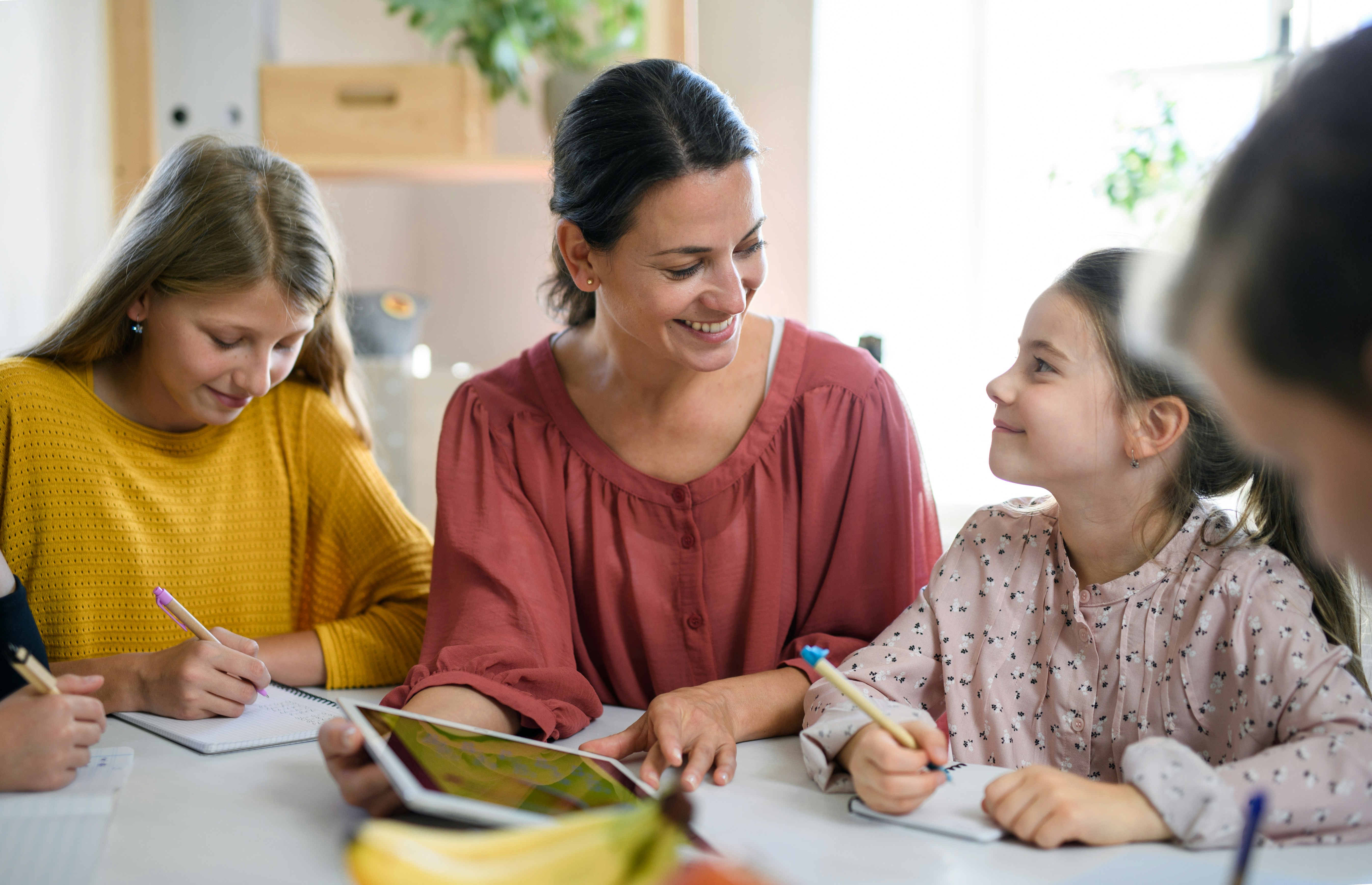 Tutor leading a small group tutoring session with three students at a shared table.