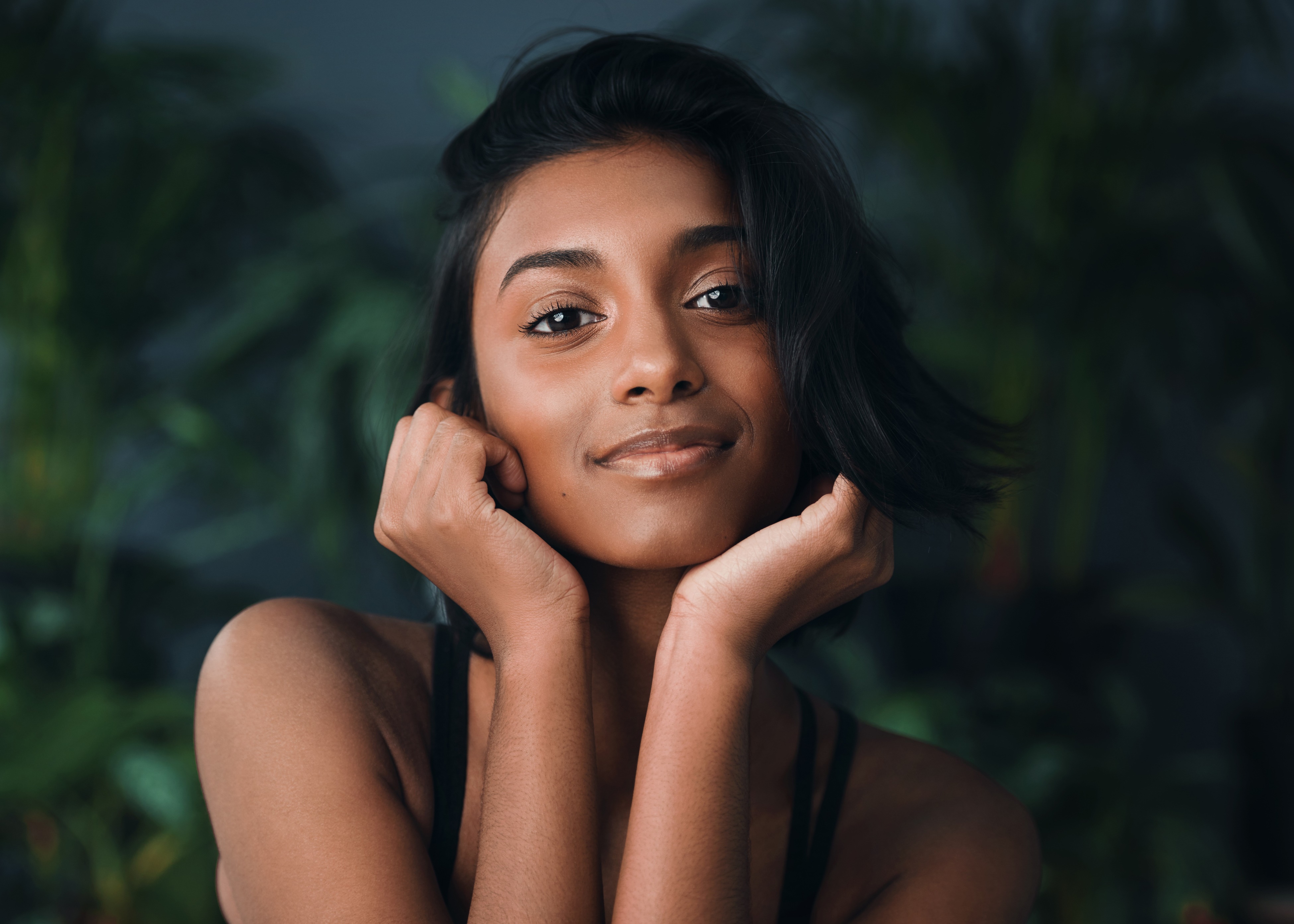 A woman posing for a picture with her hands on her face.