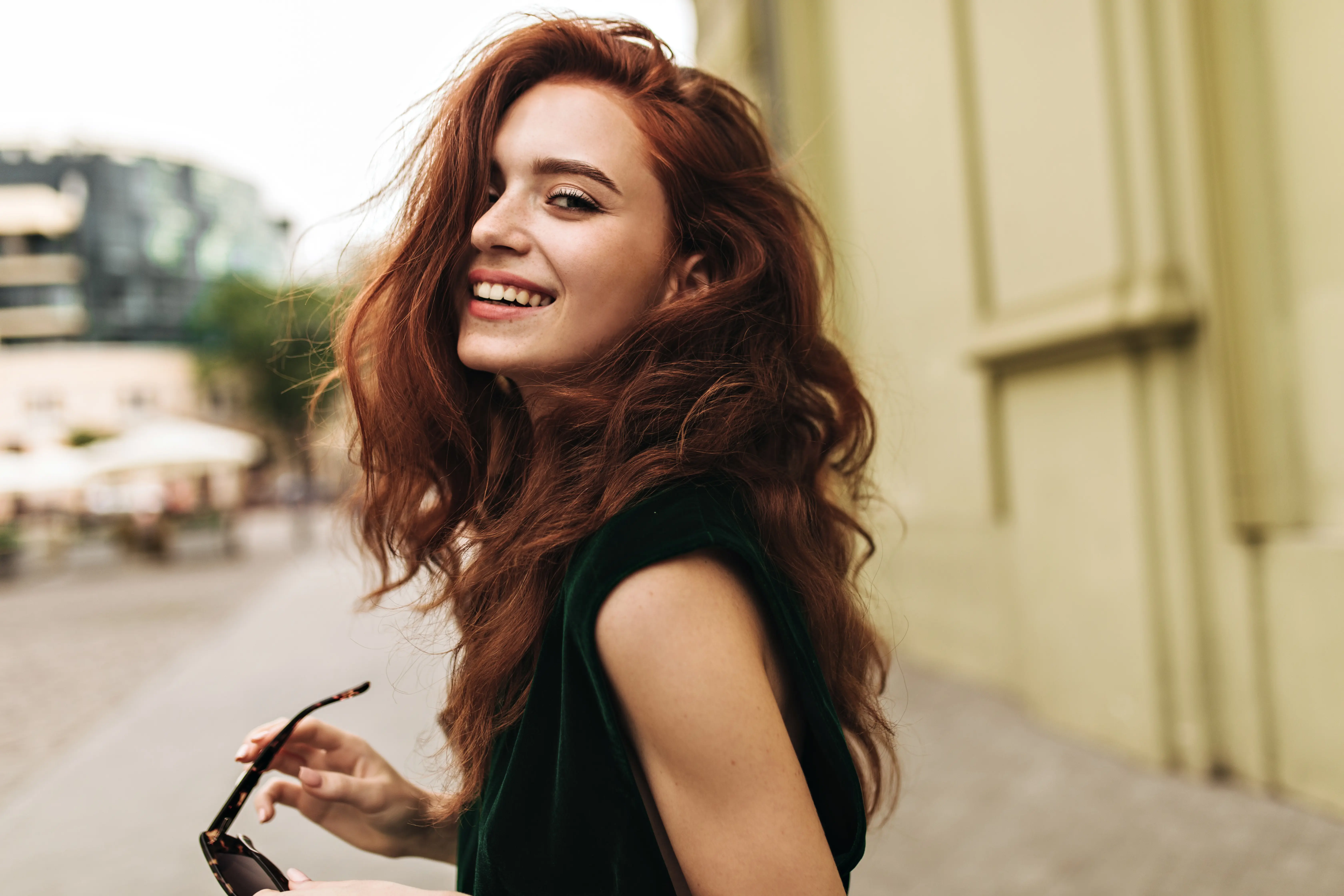 A woman with long red hair is holding a cell phone.