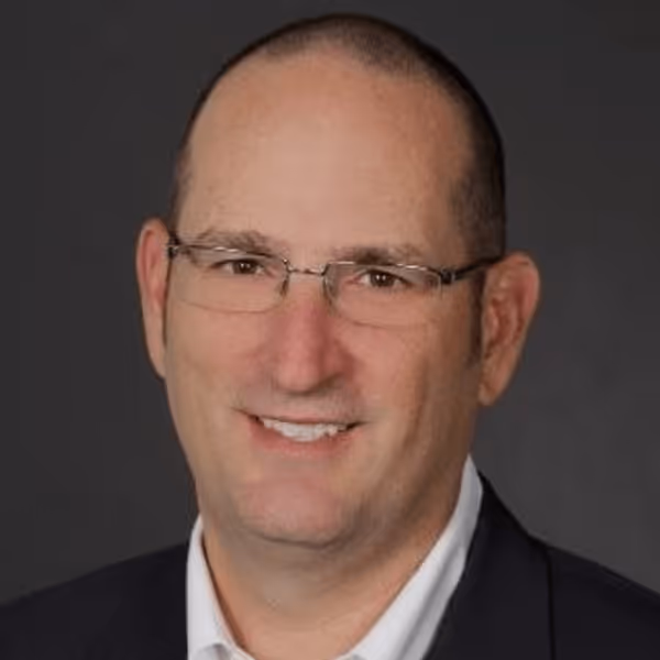 A man with a bald head and glasses smiling for the camera.