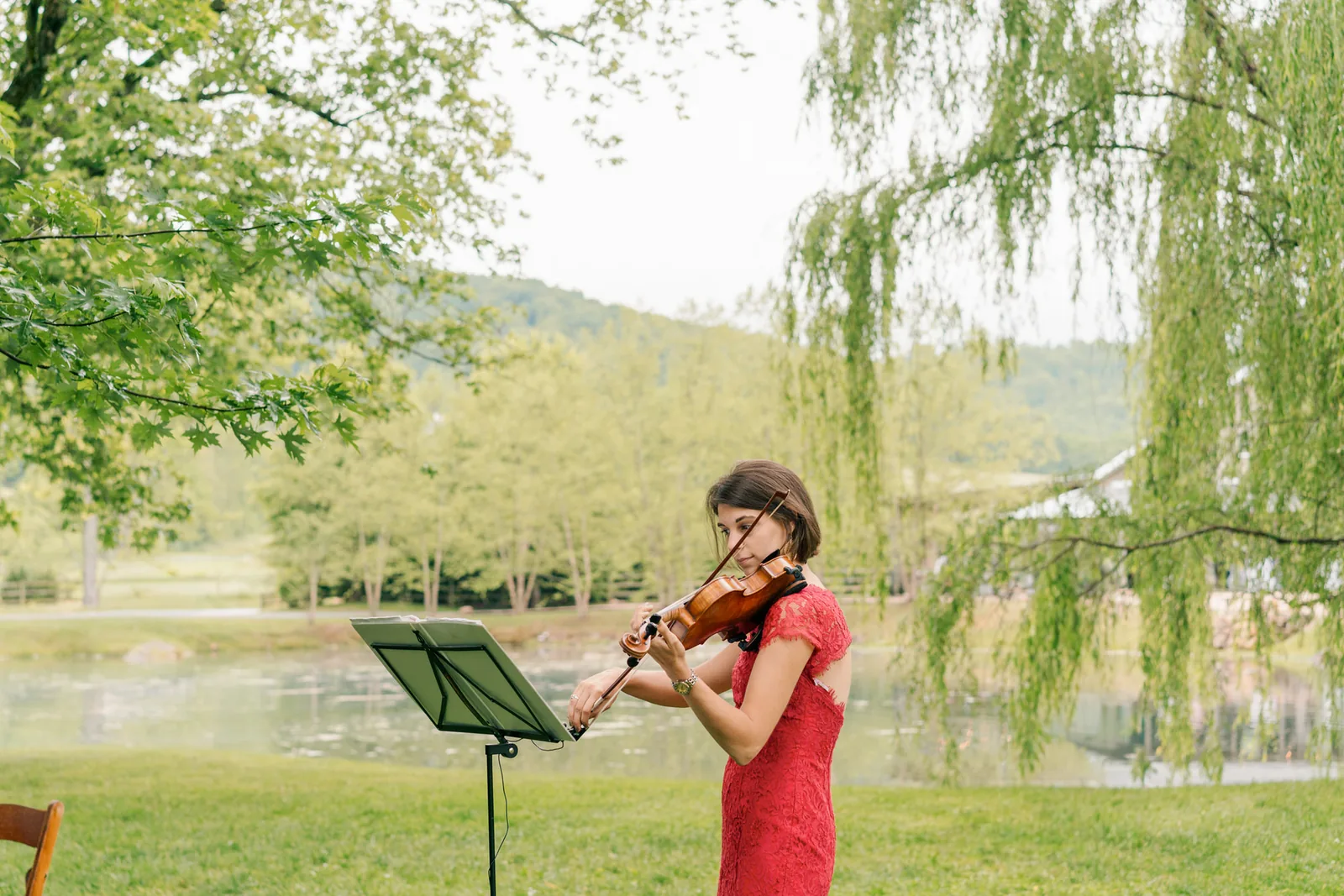 Wedding cocktail hour violinist performing live music for guests at an outdoor wedding.