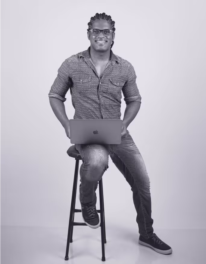 a man sitting on a stool holding a laptop