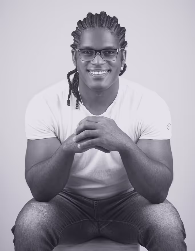 a man with braids and glasses smiling