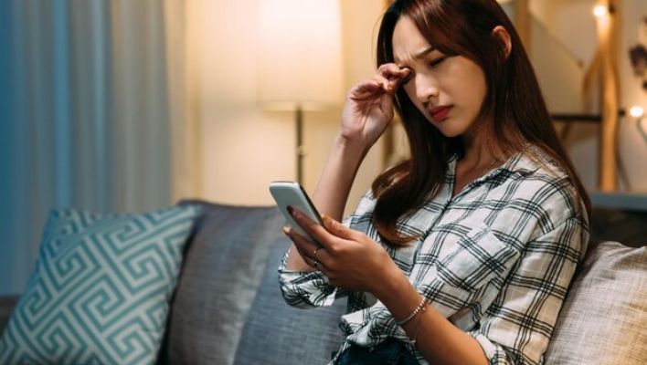 Stressed teenager experiencing digital fatigue: eye strain, poor posture, and FOMO