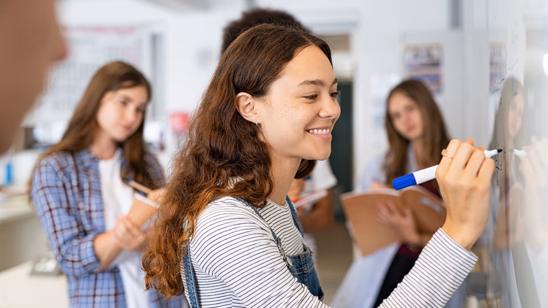 Student girl writing on whiteboard in classroom