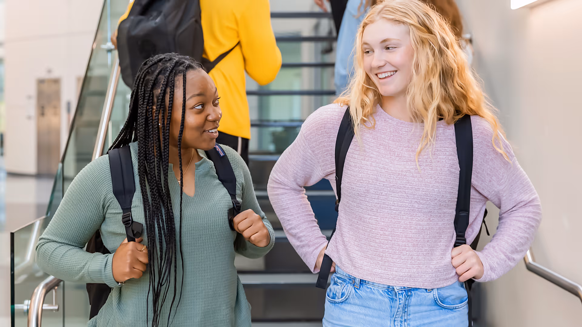 Young female college students standing at the bottom of stairs
