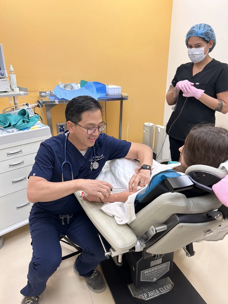 Doctor administering injection to a patient's arm while nurse stands by in a clinical setting.